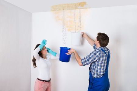 man with bucket under leaky ceiling